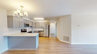 Located at 341 Fieldpointe Blvd in Frederick, MD, this single-floor residence offers a thoughtfully designed open-concept layout finished in a clean, neutral palette throughout. Light wood-look flooring extends across the main living areas, lending a cohesive and contemporary feel.

The living area is generously proportioned and anchored by a fireplace, creating a welcoming focal point. Natural light flows in through a large sliding glass door that opens to a private balcony with outdoor views. A chandelier overhead adds a refined touch to the dining and living space.

The kitchen is well-appointed with gray shaker-style cabinetry, white quartz countertops, a subway tile backsplash, and a full suite of stainless steel appliances including a refrigerator, range, microwave, and dishwasher. A central island provides additional prep and storage space.

Bedrooms are carpeted for comfort, with one featuring a bay window that brings in ample natural light. The primary bedroom includes a walk-in closet with wire shelving and direct access to a private bathroom. The bathrooms are finished with quartz vanity tops and clean white fixtures, maintaining a consistent modern aesthetic throughout the residence.