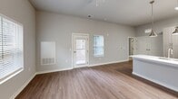 Located at 13100 Margie Ln in Raleigh, NC, this well-designed single-floor, one-bedroom, one-bathroom home offers a thoughtfully organized layout that maximizes every square foot. The open-concept living and dining area flows seamlessly into the kitchen, creating a cohesive and functional living space. Warm hardwood-style flooring runs throughout the main areas, complemented by neutral gray walls and abundant natural light from multiple windows with blinds. A ceiling fan overhead adds comfort to the living area.

The kitchen is a standout feature, equipped with stainless steel appliances — including a French door refrigerator, range, and over-the-range microwave — paired with light wood cabinetry, white subway tile backsplash, and a generous white quartz island with pendant lighting above, offering both prep space and casual dining potential.

The bedroom is carpeted for comfort and includes direct access to a walk-in closet outfitted with wire shelving. The bathroom features wood-style flooring, a sleek glass-enclosed walk-in shower with white subway tile surround, and brushed nickel fixtures.

Additional spaces include a utility room, laundry area, and a private patio, rounding out this practical and modern home.