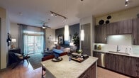 This 1-bedroom, 1-bathroom unit in Spring, TX is designed with a contemporary open-concept layout that seamlessly connects the kitchen, dining, and living areas. The kitchen is a standout feature, equipped with dark wood-grain cabinetry extending to the ceiling, light granite countertops, a subway tile backsplash, stainless steel appliances, and a central island with pendant lighting and bar seating. Wood-style flooring runs throughout the main living areas, complementing the modern aesthetic.

The living room is bright and inviting, featuring a ceiling fan, sliding glass doors that open to a private balcony, and a bold accent wall that adds visual depth. Natural light filters in through the large windows and glass doors, enhancing the open feel of the space.

The bedroom offers a carpeted floor, a generous window with outdoor views, and access to a walk-in closet. The full bathroom includes a granite-topped vanity with dark wood cabinetry, a soaking tub with a shower, and wood-style flooring. Track lighting and carefully placed pendant fixtures provide layered illumination throughout, contributing to the unit's polished, functional, and modern overall ambiance.