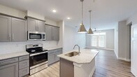 Located at 500 Dalton Way in Little River, South Carolina, this single-story, 3-bedroom, 2-bathroom home offers a thoughtfully designed open-concept layout with modern finishes throughout. The kitchen serves as the heart of the home, showcasing gray shaker-style cabinetry, granite countertops, a subway tile backsplash, and a full suite of stainless steel appliances including a side-by-side refrigerator, electric range, and built-in microwave. A central island with a undermount sink and pendant lighting flows seamlessly into the living area, which is brightened by natural light from double French doors and a ceiling fan overhead. Light wood-look flooring runs throughout the main living areas, providing a clean, cohesive aesthetic. The primary bedroom offers comfortable proportions with plush carpeting, a private en-suite bathroom featuring a granite-topped vanity with gray cabinetry, and a dedicated walk-in closet with built-in shelving. Two additional bedrooms are finished with carpet flooring, ceiling fans, and ample natural light from double windows. A second full bathroom mirrors the same refined finishes. A dedicated laundry room houses a full-size washer and dryer. Three closets provide generous storage throughout the home.