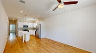 Located at 2009 S Veterans Blvd in Gonzales, Louisiana, this single-story, 3-bedroom, 2-bathroom home offers a clean, modern design with consistent light wood-style flooring running throughout every room. The open-concept living and kitchen area forms the heart of the home, highlighted by a ceiling fan overhead and recessed lighting that keeps the space bright and welcoming. The kitchen is well-appointed with crisp white shaker-style cabinetry, light gray subway tile backsplash, quartz countertops, a central island with seating, stainless steel appliances including a refrigerator, range, microwave, and dishwasher, and pendant lighting above the island. Natural light filters in through windows fitted with blinds. The three bedrooms feature neutral white walls, ceiling fans, and windows that bring in natural light, with the spacious primary bedroom offering a generous footprint. Closets include bi-fold doors with shelving and hanging rods. Both bathrooms are finished with white vanities, quartz countertops, and a tub-shower combination. A dedicated laundry area accommodates a full-size washer and dryer. The home's consistent neutral palette, modern fixtures, and functional layout make it a well-organized and practical living space.