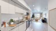 Located in Phoenix, AZ, this well-designed one-bedroom, one-bathroom residence offers a clean, contemporary aesthetic throughout its thoughtfully organized single-floor layout. Light wood-style flooring flows seamlessly across the entire space, contributing to a bright and cohesive ambiance.

The open-concept kitchen and living area serves as the heart of the home. The kitchen features sleek white cabinetry extending to the ceiling, granite-style countertops, a stainless steel sink, and a full suite of stainless steel appliances including a refrigerator, electric range, built-in microwave, and dishwasher. Recessed lighting illuminates the kitchen, which transitions naturally into the dining and living areas. The living room is generously proportioned, anchored by a large window that invites natural light and outdoor views, and is finished with a ceiling fan overhead.

The bedroom is a comfortable retreat with a sliding glass door offering direct outdoor access and additional natural light. A ceiling fan and ample wall space add to the room's practicality and comfort. An adjacent walk-in closet provides substantial storage with dual hanging rods along the perimeter.

The bathroom is clean and modern, featuring a granite-topped vanity, a glass-enclosed walk-in shower, and wood-style flooring that ties the space together. The unit's entry foyer provides a welcoming transition into the home.