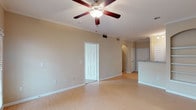 This single-floor residence offers a thoughtfully designed layout that balances open communal spaces with private retreats. The main living area is finished with light hardwood-style flooring and features crown molding, a ceiling fan, and a built-in arched shelving nook that adds architectural character to the room. Natural light fills the space through large windows and a glass-paneled exterior door with blinds, providing both brightness and privacy. The living area flows seamlessly toward the kitchen, which is separated by a granite-topped breakfast bar. The kitchen itself is well-equipped with rich dark cabinetry, granite countertops, a full suite of stainless steel appliances including a refrigerator, range, and built-in microwave, and track lighting overhead. The bedrooms are carpeted for comfort, each with a ceiling fan and ample natural light from windows with exterior views. The bathroom includes a tiled tub-and-shower combination, granite vanity countertop, and clean, neutral finishes throughout. A dedicated in-unit laundry closet houses a full-size washer and dryer, adding everyday convenience. Overall, the space presents a clean, neutral palette with consistent finishes throughout.