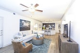 This well-designed single-story residence offers a thoughtfully arranged floor plan that balances open communal spaces with private retreats. The living room serves as the heart of the home, featuring light wood-style flooring, crown molding, a ceiling fan, and multiple windows fitted with plantation shutters that allow ample natural light. A private exterior door provides convenient outdoor access directly from the living area.

The kitchen is a standout feature, equipped with rich dark cabinetry, granite countertops, and a large center island with seating. Black and stainless steel appliances, a subway tile backsplash, and pendant lighting over the island create a polished, functional workspace. Light wood-style flooring continues throughout, connecting seamlessly to a dedicated dining area.

The residence includes multiple bedrooms, each finished with plush carpeting and ceiling fans. The primary bedroom features tray ceiling details and direct access to an en suite bathroom. Additional bedrooms offer natural light through large windows with blinds and drapery. Bathrooms are appointed with dark vanity cabinetry, white countertops, tile-surround tub-shower combinations, and wood-style flooring, providing a clean, contemporary finish throughout.
