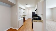 Located at 1800 Boydton Plank Rd in Petersburg, VA, this single-floor home offers four bedrooms, one bathroom, and a practical, well-organized layout. The galley-style kitchen is a functional highlight, featuring granite countertops, white cabinetry, hardwood-style flooring, and black appliances including a gas range and refrigerator. A stacked washer and dryer unit is conveniently integrated within the kitchen area, adding in-unit laundry to the home's amenities. The four bedrooms are carpeted in warm neutral tones and finished with soft, neutral-colored walls, creating a calm and comfortable atmosphere throughout. The primary bedroom is notably spacious and includes a dedicated closet with double doors, providing ample storage. Additional bedrooms are well-proportioned and receive natural light through blinded windows. Two hallways connect the rooms efficiently across the single floor. The shared full bathroom features a clean, all-white tub and shower combo with a curved curtain rod. Consistent neutral wall tones, white trim, and plush carpeting throughout the bedrooms lend a cohesive, move-in-ready aesthetic to the entire home.