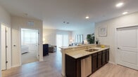 Located at 67–115 W Washington St in Oswego, Illinois, this single-floor unit offers a thoughtfully designed layout that balances functionality and comfort. The open-concept living and kitchen area serves as the heart of the space, where light wood-tone flooring runs seamlessly underfoot. The kitchen is outfitted with dark espresso cabinetry, granite countertops, and a full suite of stainless steel appliances, including a gas range, built-in microwave, refrigerator, and dishwasher. A peninsula with bar seating provides additional workspace and a casual dining option, while recessed lighting keeps the area bright and welcoming.

The living room benefits from a large sliding glass door dressed with vertical blinds, allowing ample natural light to fill the space. Neutral wall tones and clean lines give the area a calm, versatile ambiance.

The bedroom is a generously sized retreat finished with plush carpeting, a sizable window for natural light, and access to additional storage. The bathroom features wood-look luxury vinyl flooring, a granite-topped vanity with dark cabinetry, and a full tub-shower combination, maintaining the consistent design language found throughout the unit.