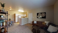 This single-floor, 1-bedroom, 1-bathroom residence offers a thoughtfully arranged layout that balances comfort and functionality. The open-concept living and dining area is anchored by warm neutral tones and plush carpeting, with a large window that invites natural light and provides pleasant outdoor views. The living space comfortably accommodates a seating arrangement, making it an inviting area to relax or entertain.

The kitchen features white cabinetry with wood-trimmed accents, light wood-style flooring, and a full suite of appliances including an electric range, dishwasher, and refrigerator. A peninsula counter separates the kitchen from the main living area, providing additional prep space and a casual dining option.

The bedroom is generously sized with soft carpeting, a ceiling fan with light fixture, and a large window that fills the room with natural light. Multiple closets, including a walk-in, offer excellent storage capacity.

The bathroom includes a tub/shower combination, a single vanity with a large mirror, wood-trimmed cabinetry for storage, and light wood-style flooring that complements the overall aesthetic of the unit.

Throughout, the warm beige walls and consistent flooring choices create a cohesive, welcoming atmosphere well-suited for comfortable everyday living.