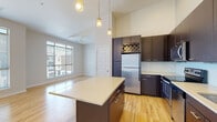 Located at 4770 Willow St in Denver's Central Park neighborhood, this single-floor residence offers a thoughtfully designed open-concept layout with impressive ceiling heights that lend a sense of spaciousness throughout the living areas. Light hardwood flooring flows seamlessly through the main living spaces, complementing the clean, contemporary aesthetic.

The kitchen is a standout feature, anchored by a central island with a light countertop surface and dark cabinetry offering ample storage. Stainless steel appliances — including a refrigerator, range, microwave, and dishwasher — are paired with a classic subway tile backsplash. Pendant lighting hangs above the island, adding warmth to the soaring ceiling above. The kitchen opens directly to the living area, which receives abundant natural light through large windows overlooking the surrounding neighborhood.

The bedroom features plush carpet, a generous walk-in closet with wire shelving, and an attached bathroom complete with a dark vanity, tiled tub-shower combination, and tile flooring. Additional rooms benefit from carpeted floors and natural light from well-placed windows. The overall ambiance is modern, clean, and well-appointed, offering a comfortable and stylish living environment.