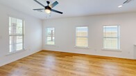 Located at 349 Ridge Rd in Lafayette, Louisiana, this single-story home offers a well-organized layout comprising three bedrooms, three bathrooms, a combined kitchen and living area, a dedicated laundry room, and a hallway connecting the private spaces. The interior is characterized by a clean, modern aesthetic, with light-toned hardwood flooring extending consistently throughout the home and crisp white walls creating a bright, cohesive atmosphere.

The open kitchen and living area serves as the central hub of the home. The kitchen features white shaker-style cabinetry, a tile backsplash, stainless steel appliances including a refrigerator and range with microwave, and a peninsula with white countertops that defines the transition into the living space. Recessed lighting overhead enhances the overall brightness.

Each bedroom is finished with the same light hardwood flooring and is equipped with a ceiling fan. The bedrooms receive natural light through windows with slatted blinds, and the primary bedroom offers direct exterior access. The three bathrooms are cleanly finished, with one featuring gray vanity cabinetry, a white countertop, and a glass-enclosed shower. The dedicated laundry room includes an LG washer and dryer set with overhead cabinetry for storage.

Outdoors, the property includes a lawned yard enclosed by a full privacy fence with a wooden gate, offering a secure outdoor space.