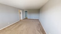 Located at 814 W Hill Ave in Knoxville, TN, this single-floor, 3-bedroom, 1-bathroom unit offers a practical and well-organized layout. The living area is generously sized, featuring neutral gray walls, plush carpeting, and a front entry door flanked by windows that allow natural light to fill the space. The kitchen is efficiently designed with warm wood cabinetry, tile flooring, a built-in sink, and a full suite of black appliances including a refrigerator, dishwasher, and range. An adjacent dining area with tile flooring provides additional functional space. The primary bedroom is notably spacious, offering ample room and direct access to a hallway. The two additional bedrooms are well-proportioned, each featuring carpet flooring, neutral gray walls, individual windows with natural light, and wall-unit HVAC systems. The bathroom is finished with tan tile walls and flooring, featuring a tub-shower combination, a window above the tub for ventilation and natural light, and a decorative tile accent border. Two closets provide convenient storage throughout the unit. The consistent use of neutral tones and carpet throughout the bedrooms creates a cohesive, move-in-ready environment.