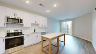 Located at 7220 Midlothian Turnpike in Richmond, VA, this modern one-bedroom, one-bathroom unit offers a thoughtfully designed layout with clean finishes throughout. The open-concept kitchen and living area serves as the heart of the home, featuring white shaker cabinetry with matte black hardware, white subway tile backsplash, light quartz countertops, and a full suite of stainless steel appliances including a refrigerator, range, microwave, and dishwasher. Warm luxury vinyl plank flooring flows throughout the main living areas, complemented by recessed lighting and large sliding glass doors that open to a private balcony with outdoor views. The spacious bedroom is finished with plush carpet, a ceiling fan, and a generous window that brings in abundant natural light. Two closets provide ample storage. The full bathroom is appointed with a white vanity, matte black fixtures, and a walk-in tile shower with a framed glass door. A dedicated laundry area and utility room add everyday convenience. Neutral tones and modern finishes create a bright, clean ambiance throughout the entire space.
