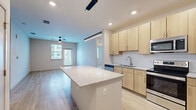 This well-appointed 2-bedroom, 2-bathroom residence features a thoughtfully designed single-level layout that maximizes functionality and comfort. The open-concept kitchen and living area serves as the heart of the home, highlighted by a large granite-topped island with pendant lighting overhead. The kitchen is outfitted with light wood cabinetry, a subway tile backsplash, granite countertops, and a full suite of stainless steel appliances including a refrigerator with ice maker, range, microwave, and dishwasher. Light wood-style flooring runs throughout the main living areas, complementing the bright, neutral color palette. The living room features a ceiling fan and access to natural light through windows overlooking the exterior. Both bedrooms are carpeted for comfort, with the secondary bedroom offering dual windows and the primary bedroom featuring a spacious closet with double doors. The two bathrooms are finished with clean, modern tile work — one includes a soaking tub with large-format wall tile, while the other offers a glass-enclosed walk-in shower with a granite-topped vanity and wood-toned cabinetry. The overall ambiance is clean, contemporary, and move-in ready.