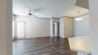 This single-floor residence offers a thoughtfully designed layout that balances open communal areas with comfortable private spaces. The living and dining areas are finished with rich, dark hardwood-style flooring that extends throughout the main living zones, complemented by crown molding and a ceiling fan that add a polished touch. A pendant light fixture anchors the dining area, while large windows fitted with blinds allow natural light to fill the space.

The kitchen features dark espresso-toned cabinetry with sleek bar-pull hardware, crisp white countertops, a stylish linear mosaic tile backsplash, and stainless steel appliances including a range and microwave. A breakfast bar connects the kitchen to the main living area, enhancing the open flow.

The bedrooms are carpeted for comfort and each includes a ceiling fan with light, as well as windows that bring in natural light. The rooms offer generous proportions suited to a variety of furniture configurations.

Two full bathrooms mirror each other in design, each featuring a dark wood vanity with a white undermount sink, a large mirror with overhead lighting, and a tiled shower-tub combination. The overall palette of neutral tones throughout the residence creates a clean, move-in-ready environment.
