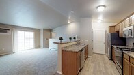 This single-floor unit offers a thoughtfully designed layout that balances functionality and comfort. The kitchen is a standout feature, showcasing warm medium-toned wood cabinetry, granite-look countertops, stainless steel appliances including a refrigerator, range, and microwave, and light wood-look vinyl plank flooring. A peninsula with additional counter space connects the kitchen to the open living area, which is finished with plush wall-to-wall carpeting and a sliding glass door that invites natural light and outdoor access. The spacious living area also includes a baseboard heating system, providing efficient warmth throughout.

The unit includes two generously sized bedrooms, each carpeted and equipped with ceiling fans, natural light from windows, and baseboard heating. The neutral color palette throughout creates a calm and versatile backdrop. Two bathrooms serve the unit: one features a tub-shower combination, wood-toned cabinetry, granite-look countertops, and wood-look flooring; the second offers a standalone shower stall with matching cabinetry and countertop finishes. Both bathrooms are clean and practical in design. The overall ambiance is bright, neutral, and move-in ready.