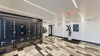 Located at 5460 Fountain Ave in the heart of Los Angeles, CA, this contemporary building lobby delivers a polished and well-appointed first impression. The space is defined by a bold, geometric patterned floor composed of marble-effect and dark gray tiles arranged in a dynamic, offset layout that draws the eye throughout the area. Recessed linear LED lighting runs across the smooth white ceiling in clean, parallel lines, casting bright, even illumination across the entire lobby. A prominent wall-mounted bank of individual mailboxes, finished in sleek black, serves as a central functional element and is framed by dark reflective tile cladding that adds depth and contrast to the interior. Elevator access is provided via stainless steel elevator doors set against similarly dark tile surrounds, accompanied by a tufted built-in bench offering a comfortable waiting area. Curated wall art and potted tropical plants, including a tall cactus, add warmth and character to the otherwise minimalist aesthetic. White walls provide a neutral backdrop that highlights these carefully placed decorative touches. The overall ambiance is modern, clean, and professional, reflecting a thoughtfully designed communal space suited to the vibrant Los Angeles urban environment.