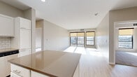 This well-appointed single-floor residence offers a clean, contemporary design throughout. The open-concept layout connects the kitchen and living area seamlessly, creating a bright and airy atmosphere enhanced by large floor-to-ceiling windows and light wood-style flooring. The living area is bathed in natural light and provides direct access to a private balcony, offering sweeping views of the surrounding urban landscape.

The kitchen is a standout feature, outfitted with crisp white shaker cabinetry, a classic white subway tile backsplash, stainless steel appliances including a refrigerator, range, built-in microwave, and dishwasher, and a generous quartz-topped island ideal for meal prep or casual dining. A stainless steel sink with a gold-toned faucet adds a refined touch.

The two bedrooms are carpeted for comfort, each receiving ample natural light through large windows with city views. Both spaces offer a calm, neutral palette that lends itself to versatile furnishing arrangements.

Two full bathrooms serve the unit, each featuring a tub-shower combination, white vanity with integrated sink, and tile flooring, presenting a clean and functional design. The overall aesthetic is modern and move-in ready, with neutral tones and thoughtful finishes throughout.