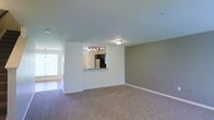 Located at 650 Bentley Ridge Boulevard in Lancaster, Pennsylvania, this two-floor residence offers a well-designed layout with comfortable, functional living spaces. The main living area is open and spacious, featuring neutral-toned carpeting and light gray walls that create a calm, welcoming atmosphere. Natural light filters in through a large window, brightening the room and enhancing its airy feel.

A standout architectural detail is the pass-through window connecting the living area to the kitchen, which promotes an open, connected feel between the two spaces. The kitchen is outfitted with dark cabinetry, stainless steel appliances including a full-size refrigerator, granite-style countertops, and track lighting overhead — providing both style and practicality. The adjacent hallway leads to additional areas of the home, suggesting a thoughtfully organized floor plan.

The overall color palette is neutral and modern, with clean white trim and baseboards complementing the soft wall tones. The two-floor layout offers a separation of living and private spaces, making it well-suited for everyday living. The combination of practical finishes, an open-concept design, and a convenient Lancaster location makes this a well-rounded residential space.