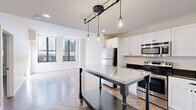 Located at 1214 Woodward Ave in the heart of Detroit, MI, this one-bedroom, one-bathroom residence offers a thoughtfully designed layout with refined finishes throughout. The open-concept living and kitchen area serves as the heart of the unit, showcasing eye-catching herringbone-patterned hardwood flooring that flows seamlessly through every room. Large, floor-to-ceiling windows flood the living space with abundant natural light and offer views of the surrounding urban landscape, enhancing the airy, open ambiance.

The kitchen is well-appointed with crisp white shaker cabinetry, dark granite countertops, stainless steel appliances including a full-size refrigerator, microwave, range, and dishwasher, complemented by open metal shelving and an industrial-style pendant light fixture above a mobile kitchen island.

The bedroom is a comfortable, well-proportioned retreat, continuing the herringbone flooring and benefiting from its own set of large windows that bring in generous natural light. The bathroom features marble-look tile flooring, a sleek dark-finished vanity with a framed mirror, and a glass-enclosed walk-in shower, creating a clean, modern aesthetic throughout.