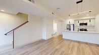Located at 10723 Cedar Ave in Cleveland, OH, this contemporary 3-story home offers a thoughtfully designed layout spread across three distinct levels. The ground floor houses an attached garage with an automatic opener, concrete flooring, cinder block accents, and interior access via a staircase leading to the main living areas.

The main level features a bright, open-concept living, dining, and kitchen space finished with light hardwood flooring and crisp white walls. The modern kitchen is anchored by a large island with a light quartz countertop, white shaker cabinetry, stainless steel appliances, and stylish pendant lighting. A convenient half bathroom with a window and clean vanity finishes this floor.

The upper level hosts two bedrooms, including a generously sized primary bedroom with multiple windows, a walk-in closet accessible through a sliding barn door, and light-filled views of the neighborhood. The second bedroom also enjoys natural light through large windows. Both bedrooms share well-appointed bathrooms. A dedicated laundry area, pantry, and ample closet storage add practical convenience. A private balcony extends the living space outdoors, while a bonus room provides additional flexibility. Throughout, two-panel white doors with matte black hardware lend a clean, modern aesthetic.