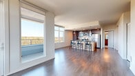 Located in Portland's vibrant Northeast neighborhood, this thoughtfully designed 3-bedroom, 2-bathroom residence offers a seamless blend of modern style and functional living across a single floor. The open-concept living and kitchen area serves as the heart of the home, showcasing rich dark hardwood flooring, floor-to-ceiling windows, and direct access to a private balcony that frames sweeping panoramic views of the surrounding treetops and cityscape. The kitchen is outfitted with stainless steel appliances, dark cabinetry, a subway tile backsplash, and a central island with a stone countertop and bar seating beneath stylish pendant lighting. The primary bedroom is a bright, airy retreat with large windows and balcony access, flooding the space with natural light. It includes a walk-in closet equipped with built-in wire shelving. Additional bedrooms are carpeted and well-lit with natural light. Both bathrooms feature clean, contemporary finishes, including wood-toned vanities and stone-look countertops. Hallways connect the rooms efficiently, and the neutral white walls throughout create a crisp, cohesive aesthetic. The space combines urban convenience with refined residential comfort.
