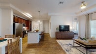 Located at 2098 Seminole Blvd in Largo, Florida, this single-floor residence offers a thoughtfully designed open-concept layout that seamlessly connects the kitchen, dining, and living areas. Rich hardwood-style flooring flows throughout the main living spaces, creating a warm and cohesive aesthetic.

The kitchen is a standout feature, equipped with stainless steel appliances, rich dark wood cabinetry, granite countertops, and a central island with bar seating illuminated by pendant lighting. A dedicated dining area adjacent to the kitchen provides additional space for entertaining. A side-by-side washer and dryer are conveniently situated just off the kitchen.

The living room is generously proportioned, featuring a tray ceiling with accent color, large French doors that invite natural light, and a comfortable, stylish layout. A separate dining nook off the kitchen adds versatility to the floor plan.

The bedrooms offer a calm retreat with plush carpeting and ample space. The bathrooms are well-finished, featuring dark wood vanities with granite countertops, full-size mirrors, and hardwood-style flooring. One bathroom includes a tub-shower combination with classic tile surround, alongside a walk-in closet. The overall ambiance is modern, warm, and livable throughout.