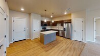 Located on Prairie Grove Ave S in Fargo, North Dakota, this single-floor unit offers a well-designed, open-concept layout that connects the kitchen and living areas seamlessly. The kitchen is a standout feature, showcasing rich dark-stained cabinetry, light quartz countertops, and a full suite of stainless steel appliances including a refrigerator with ice and water dispenser, electric range, and over-the-range microwave. A central island with a quartz surface provides additional prep space, while pendant lighting adds a refined touch. Light hardwood-style flooring runs throughout the kitchen and dining area, transitioning to plush carpet in the living room and bedrooms.

The spacious living area benefits from large windows that invite abundant natural light and offer neighborhood views. A built-in desk nook adds functional versatility to the space. The unit includes two full bathrooms: one features a tub-shower combo with light wood-style flooring and a single vanity, while the primary bathroom offers a walk-in shower, an extended double vanity with dark cabinetry, and direct access to a walk-in closet equipped with wire shelving. Bedrooms are carpeted and well-lit by generous windows. The overall aesthetic is clean, neutral, and move-in ready.