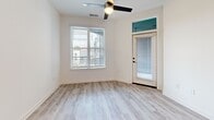 Located at 2314 Berryhill Rd in Charlotte, NC, this single-floor, one-bedroom, one-bathroom unit delivers a clean, modern aesthetic with high-quality finishes throughout. Light gray wood-look flooring runs continuously across all rooms, creating a cohesive and airy feel. The living room is bright and welcoming, featuring a ceiling fan, a large window with natural light, and a glass-paneled entry door with a transom window above. The standout kitchen is designed with bold navy blue lower cabinets contrasted against crisp white upper cabinetry and white quartz countertops. A herringbone tile backsplash, stainless steel appliances—including a refrigerator, range, and over-the-range microwave—and a deep single-basin sink with a matte black faucet complete the well-equipped space. The bedroom is comfortably sized with its own ceiling fan, a window with natural light, and access to a dedicated closet. A hallway connects the main living areas to the private spaces seamlessly. The bathroom features a full soaking tub with white subway tile surround, built-in open shelving, a white vanity with matte black hardware, and wood-look flooring that ties the space together. Clean white walls and consistent matte black fixtures throughout unify the home's contemporary design.