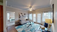 Located at 5701 Saratoga Blvd in Corpus Christi, Texas, this single-floor residence offers a well-designed, open layout that connects the main living areas seamlessly. The kitchen is equipped with warm wood cabinetry, black appliances including a refrigerator, range, and dishwasher, and features a curved breakfast bar island with bar seating — ideal for casual dining or entertaining. Crown molding and wood-style flooring extend throughout the main areas, adding a polished, cohesive look. Adjacent to the kitchen, a dedicated dining nook provides an intimate space for meals. The living room is bright and inviting, with a ceiling fan, crown molding, French doors that welcome natural light, and direct access to an outdoor area. Two bedrooms are carpeted and feature ceiling fans and ample window coverage with blinds and curtains for privacy. The primary bathroom includes a dual-sink vanity with wood cabinetry and a shower/tub combo. A second full bathroom offers similar finishes. A laundry area with washer and dryer connections is conveniently accessible from within the unit. Throughout the residence, neutral tones and consistent finishes create a comfortable and functional living environment.