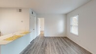 Located at 345 Bryant Rd in Spartanburg, South Carolina, this single-story residence offers a clean, functional layout with a thoughtful mix of finishes throughout. The open living area welcomes you with smooth wood-look flooring and bright white walls, with multiple windows dressed in horizontal blinds that invite generous natural light and views of the surrounding greenery. The space flows seamlessly into the kitchen, which is a standout feature of the home. Rich, dark espresso-toned cabinetry is paired with crisp white subway tile backsplash and light countertops, creating a striking contrast. Black appliances, including a range and overhead ventilation, complement the kitchen's bold aesthetic, while recessed lighting and under-cabinet illumination ensure excellent visibility. A peninsula counter provides additional prep space and casual dining opportunity. The bedrooms are carpeted in a warm, neutral tone, providing comfort underfoot, with windows offering peaceful outdoor views and ample natural light. An in-unit washer and dryer area adds everyday convenience. The bathroom features a classic layout with a shower/tub combination, accented by a bold black-and-white striped curtain. Throughout, the space maintains a neutral, move-in-ready palette ideal for a variety of lifestyles.