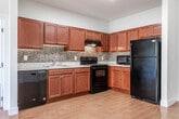 Located at 255 E Grand Ave in Rahway, NJ, this single-floor residence offers a thoughtfully designed layout with a clean, neutral palette throughout. The kitchen is a standout feature, showcasing rich cherry wood cabinetry, a mosaic tile backsplash, light stone countertops, and a full suite of black appliances including a range, dishwasher, refrigerator, and microwave. Warm hardwood-style flooring extends through the kitchen and living areas, adding a welcoming continuity to the space. The bedrooms are carpeted for comfort and receive generous natural light through large windows fitted with blinds. One bedroom offers views of an interior courtyard, while another looks out to lush greenery. Both rooms include wall-mounted HVAC units for individual climate control. The walk-in closet is equipped with wire shelving and hanging rods, providing ample organized storage. Two full bathrooms serve the unit — one featuring a tub-shower combination and the other a glass-enclosed standing shower — both finished with tile flooring, rich cherry wood vanities, cream countertops, and well-lit mirrors. The overall design is cohesive and functional, blending classic finishes with practical amenities in a comfortable residential setting.