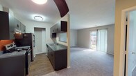 Located at 7477 Shady Water Lane in Dayton, Ohio, this single-floor unit offers a practical and well-organized layout designed for comfortable everyday living. The galley-style kitchen is outfitted with dark espresso cabinetry, gray laminate countertops, a stainless steel sink, electric range, refrigerator, and dishwasher. Wood-look flooring runs throughout the kitchen, lending a clean, contemporary feel. A pass-through window connects the kitchen to the adjacent living area, enhancing the sense of openness between the spaces. The spacious living room features neutral wall-to-wall carpeting and is filled with natural light from a large sliding glass door that opens to an outdoor view, making the room feel bright and inviting. A separate bedroom continues the carpeted flooring with a window that brings in additional natural light, complemented by a closet for convenient storage. The full bathroom is thoughtfully appointed with a tub-shower combination, toilet, and a vanity featuring matching dark cabinetry and gray countertops, with wood-look flooring tying the finishes together. Throughout the unit, neutral tones and consistent design elements create a cohesive and functional living environment suited for a variety of lifestyles.