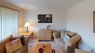 This three-floor residence is thoughtfully laid out across its levels, offering a range of functional and comfortable living spaces. The main living area features carpet flooring and a large window dressed with vertical blinds, allowing natural light to filter through while maintaining privacy. The galley-style kitchen is efficiently designed with dark espresso cabinetry lining both walls, light countertops, tile flooring, and a full suite of white appliances including a refrigerator, range, and dishwasher.

The bedrooms are carpeted and well-proportioned, each offering ample storage through sliding-door closets with built-in shelving and hanging rods. One bedroom is notably spacious with a large window overlooking the exterior, while a second bedroom provides a more intimate setting. Two bathrooms serve the home: a half bath with a pedestal-style sink and a large mirror, and a full bath featuring a wide vanity with generous counter space, a tub-shower combination, tile flooring, and a window for natural light.

The finished lower level provides additional living space with carpet, small hopper windows, and room for seating or recreation. A separate utility area houses the furnace and water heater, keeping mechanical systems organized and accessible.