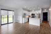 Located at 144 Watson Rd N in Guelph, Ontario, this modern 2-bedroom, 2-bathroom unit offers a thoughtfully designed open-concept layout finished with clean, contemporary details throughout. Light hardwood-style flooring runs continuously across the entire space, enhancing the sense of openness and warmth.

The kitchen is a standout feature, outfitted with sleek white cabinetry, light quartz countertops, a subway tile backsplash, stainless steel appliances, and a central island with pendant lighting — ideal for both cooking and casual dining. The kitchen flows seamlessly into the living area, which is brightened by large black-framed windows offering treetop and cityscape views.

The spacious primary bedroom features large windows that flood the room with natural light and provide scenic outdoor views, along with a walk-in closet equipped with built-in shelving and hanging storage. The second bedroom is well-proportioned with easy access to the hallway. Both bathrooms are finished with neutral tile flooring; one features a glass-enclosed walk-in shower. Two closets provide ample storage throughout the unit.

The overall ambiance is bright, clean, and modern, making this a well-appointed space in a residential Guelph community.