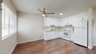 Located at 9012 Casals St in Sacramento, California, this efficiently designed single-floor unit makes smart use of its compact footprint. Rich, dark hardwood-style flooring runs throughout the space, lending warmth and visual continuity to every room.

The open-concept kitchen and living area form the heart of the unit. The kitchen is outfitted with crisp white cabinetry extending from floor to ceiling, light countertops, a double-basin sink, an electric range with overhead ventilation, and a full-size refrigerator. A ceiling fan with integrated lighting anchors the combined living space, promoting airflow and comfort. A wall-mounted HVAC unit and a window overlooking the exterior complete the living area.

The unit includes two bathrooms. One features a soaking bathtub with white subway tile surround, while the other is a more functional space that incorporates an in-unit washer and a vessel sink set atop a white vanity with stone-look countertops and a large mirror. A dedicated closet with a hanging rod provides organized storage.

The clean, neutral color palette of white walls and bright finishes throughout creates a light, airy atmosphere, making the space feel open and easy to personalize.