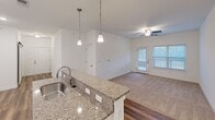This contemporary 900 square foot apartment offers a blend of style and functionality. The open-concept living area seamlessly integrates the kitchen and living room, creating an expansive feel. The kitchen boasts white cabinetry, granite countertops, and stainless steel appliances, including a built-in microwave. Pendant lighting adds a touch of elegance.

The two bedrooms feature plush carpeting and large windows, with the primary bedroom measuring 150 square feet. The bathroom showcases a granite vanity top and wood-look flooring. A notable amenity is the in-unit laundry room with full-sized, stacked washer and dryer.

Throughout the apartment, wood-look flooring enhances the modern aesthetic. Recessed lighting and ceiling fans provide both ambiance and comfort. The space is bathed in natural light thanks to multiple windows with horizontal blinds.

Storage is ample with three closets distributed throughout the unit. The apartment's single-story layout and neutral color palette create a versatile canvas for various decorating styles. Located at 1310 Covered Bridge View in Suffolk, VA, this apartment combines contemporary design with practical living spaces.