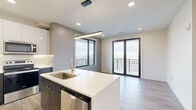 Located at 4201 S Navajo St in Englewood, Colorado, this single-floor residence showcases a contemporary design aesthetic defined by clean lines, neutral tones, and high-quality finishes. The open-concept living and kitchen area serves as the heart of the unit, where light wood-tone flooring flows seamlessly underfoot and recessed lighting illuminates the space from above. A sleek linear pendant light anchors the central kitchen island, which features a white quartz countertop, an undermount stainless steel sink, and dark cabinetry below. The kitchen is fully equipped with stainless steel appliances, including a refrigerator, electric range, microwave, and dishwasher, complemented by a two-tone cabinet arrangement of dark lower units and crisp white upper cabinets.

The living area opens directly to an outdoor balcony through black-framed glass doors, with an adjacent large window framing open exterior views—filling the space with generous natural light. The bedrooms are carpeted for comfort, with one featuring a ceiling fan and another benefiting from a large picture window with elevated outdoor views.

The bathroom presents a refined, minimalist design with large-format tile flooring, a wide-format mirror, white quartz countertop, and a navy blue wood-grain vanity with brushed nickel fixtures. Throughout the unit, the modern finishes and thoughtful layout create a cohesive, contemporary living environment.
