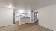 Located at 2074 Midyette Rd in Tallahassee, FL, this single-floor residence offers a practical and well-organized layout with two bedrooms and two bathrooms. The open-concept living and dining area is finished with plush carpeting and flows seamlessly toward a windowed wall fitted with vertical blinds, allowing natural light to fill the space. A ceiling fan anchors the living area, adding both function and comfort. The kitchen features white cabinetry, open shelving, white appliances, and a peninsula counter that serves as a natural divider between the kitchen and living areas. Durable hardwood-style flooring runs through the kitchen and entry zones, complementing the neutral, light-filled interior. The primary bedroom is a comfortable, carpeted retreat with access to a dedicated closet space outfitted with wire shelving and hanging rods — offering generous storage on hardwood-style flooring. The bathrooms are clean and functional, with one featuring a full tub-shower combination finished in classic white subway tile. A second closet provides additional storage throughout the home. The overall aesthetic is clean and neutral, with white walls throughout, making the space easy to personalize.