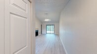 Located in Sun Valley Village in Altamonte Springs, Florida, this 2-bedroom, 2-bathroom residence offers a thoughtfully designed single-floor layout with a bright, airy ambiance throughout. The living room is a standout space, featuring vaulted ceilings, a ceiling fan, and a fireplace, all anchored by light wood-style flooring. A sliding glass door fills the room with natural light and provides outdoor access. The adjacent kitchen is well-equipped with warm wood cabinetry, dark granite-style countertops, tile flooring, and black appliances including a refrigerator, electric range, and dishwasher. The open flow between the kitchen and living areas adds to the sense of spaciousness. The primary bedroom offers comfortable carpeted flooring, a window with natural views, and an en-suite bathroom featuring a walk-in shower with glass doors, a wood-toned vanity, and granite-style countertops. The second bedroom is carpeted and includes a wide bi-fold closet. The second bathroom provides a tub/shower combo and matching vanity finishes. A dedicated laundry area houses a full-size washer and dryer with wire shelving above for added storage, completing this functional and inviting home.