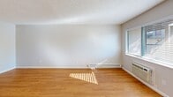 Located at 394 Boynton Ave in San Jose, California, this efficiently designed single-floor unit offers a functional layout comprising a living room, kitchen, bathroom, and closet. Throughout the space, warm honey-toned hardwood-style flooring provides a cohesive and inviting foundation, complemented by neutral gray walls and white trim.

The living room is bright and open, benefiting from natural light that streams through windows fitted with blinds. A textured popcorn ceiling adds character overhead, while a baseboard heater and wall-mounted AC unit ensure year-round climate comfort. The clean, open walls offer flexibility for a variety of furniture arrangements.

The kitchen is neatly appointed with white cabinetry, a white refrigerator, and a gas range, all illuminated by a flush-mount ceiling light. A pass-through counter connects the kitchen to the living area, enhancing the sense of openness. Windows in the kitchen allow for additional natural light.

The closet is a generous walk-in style space featuring dual hanging rods along two walls, providing practical and ample storage. The bathroom completes the layout, maintaining the clean, simple aesthetic found throughout the unit.

Overall, the space presents a clean, minimalist aesthetic with consistent finishes, making it a practical and comfortable residence in San Jose's West Side neighborhood.