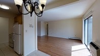 This single-floor residence offers a practical and inviting layout across two bedrooms and one bathroom. The open living and dining area forms the heart of the home, featuring warm hardwood flooring that extends throughout the main living spaces, creating a cohesive and welcoming atmosphere. Neutral white walls provide a clean, versatile backdrop that complements a variety of décor styles. A decorative wrought-iron chandelier adds a touch of character to the dining area, which transitions seamlessly into the spacious living room. Tile flooring in the entryway offers a durable and easy-to-maintain surface at the threshold. A baseboard heating system lines the perimeter of the living room, ensuring comfortable warmth throughout the cooler months. The layout flows naturally from the entry through the main living spaces toward the hallway, which leads to the private bedrooms and bathroom. Ample natural light fills the interior, enhancing the bright, airy feel of the open floor plan. This residence combines classic design elements with functional living spaces, making it an ideal home for those seeking comfort and simplicity in a well-maintained setting.