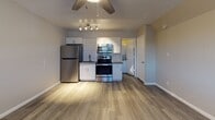 Located in Glendale, Arizona, this efficiently designed studio offers a smart, functional layout across a single floor. The open living area features durable wood-look plank flooring in a warm gray tone, a textured ceiling, and a ceiling fan with a light fixture that keeps the space comfortable year-round. A wall-mounted air conditioning unit provides additional climate control, while a window with blinds allows natural light to filter in and offers views of the surrounding neighborhood.

The kitchen is a standout feature, outfitted with a full suite of stainless steel appliances including a refrigerator, electric range, and over-the-range microwave. White shaker-style cabinetry with brushed nickel hardware lines the walls, complemented by a classic white subway tile backsplash and a single-basin sink. Track lighting above the kitchen area adds focused illumination. The bathroom includes a full soaking tub with a shower, finished with clean white surrounds and brushed nickel fixtures, maintaining a crisp, utilitarian aesthetic throughout. The overall design is modern and move-in ready, ideal for those seeking a no-frills, well-appointed studio living space.
