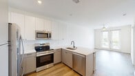 Located at 900 N Allen Ave in Richmond, VA, this 2-bedroom, 1-bathroom apartment offers a thoughtfully designed single-floor layout with modern finishes throughout. Light-toned hardwood-style flooring runs continuously across the living spaces, creating a cohesive and clean aesthetic.

The open-concept kitchen and living area serves as the heart of the unit. The kitchen is outfitted with white cabinetry, a white quartz peninsula with an undermount sink, a tile backsplash, and a full suite of stainless steel appliances including a French door refrigerator, electric range, and over-the-range microwave.

The primary bedroom is a well-proportioned space featuring a stylish sliding barn door that connects to the bathroom, adding a contemporary architectural detail. The second bedroom is bright and airy, benefiting from large windows that frame outdoor views of the surrounding Richmond neighborhood. The living area also features a set of glass French doors with a ceiling fan, opening to an outdoor space and allowing abundant natural light.

The bathroom is finished with neutral tile flooring, a combination tub and shower with a curved rod, and brushed nickel fixtures. The overall color palette of soft whites and warm wood tones creates a clean, modern ambiance throughout this efficiently designed Richmond apartment.