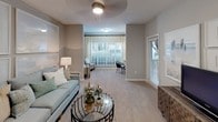 This single-floor residence offers a thoughtfully designed layout that balances comfort and functionality throughout. The entry foyer features tile flooring and an elegant arched passageway that leads into the dining and living areas, setting a welcoming tone from the moment you arrive. The kitchen is outfitted with dark espresso cabinetry, granite countertops, a stone tile backsplash, stainless steel appliances including a gas range and built-in microwave, and a double-basin sink — providing a well-equipped space for cooking and entertaining. The open living and dining area is finished with plush carpet and benefits from multiple windows that invite abundant natural light. The living room features a cozy seating arrangement accented by large framed artwork. The primary bedroom is generously sized with multiple windows, a ceiling fan, and ample space for a full furniture suite. A secondary bedroom includes a walk-in closet and soft carpeting. Both bathrooms are finished with granite-topped vanities, dark cabinetry, wood-look flooring, large mirrors with bright vanity lighting, and a tub-shower combination. Throughout the residence, a cohesive soft gray and beige color scheme creates a calm, contemporary ambiance.