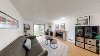 Located at 4600 Davis Ave S in Renton, WA, this single-floor, 2-bedroom residence offers a well-organized layout with a combined living and dining room, a dedicated kitchen, a hallway, three closets, and a private patio. The living and dining area serves as the heart of the home, highlighted by a classic brick fireplace, light-toned hardwood flooring, a textured ceiling, and a sliding glass door that opens to the patio and brings in natural light while framing views of the surrounding greenery. Track lighting adds a modern touch to the space. The kitchen features white cabinetry with black hardware, dark countertops, stainless steel appliances including a refrigerator and dishwasher, and a window with blinds that allows natural light to filter in. A peninsula counter connects the kitchen to the dining area, creating an open and functional flow. Both bedrooms are carpeted and offer sliding-door closets, with the primary bedroom providing a comfortable, well-proportioned retreat with a window overlooking mature trees. The bathroom includes a full tub and shower combination. Throughout the home, a neutral color palette and clean finishes contribute to a bright, cohesive ambiance.
