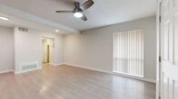 This thoughtfully laid-out 1-bedroom, 1-bathroom unit offers a clean, modern aesthetic with consistent light wood-toned flooring flowing throughout every room. The open living area is bright and airy, featuring a ceiling fan with integrated lighting, recessed lights, and large vertical-blind-covered windows and a sliding door that allow generous natural light to fill the space. Neutral gray-toned walls provide a versatile backdrop throughout. The kitchen is well-appointed with white shaker-style cabinetry, a classic white subway tile backsplash, stainless steel appliances including a refrigerator, electric range, over-the-range microwave, and dishwasher, plus a stainless steel sink. The bedroom offers a comfortable footprint with multiple windows dressed in horizontal blinds, providing ample natural light and views of surrounding greenery. The bathroom features a full soaking tub and shower combination with elegant large-format marble-look tile surround and chrome fixtures. Additional conveniences include a hallway, a dedicated closet for storage, and a well-connected layout that maximizes efficient use of the available space. Overall, the unit presents a clean, contemporary feel ideal for comfortable everyday living.