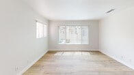 Located in Santa Clarita, CA, this single-story 2-bedroom, 2-bathroom home offers a clean, bright layout designed for comfortable everyday living. The open-concept living, dining, and kitchen area serves as the heart of the home, with light hardwood flooring that extends throughout the main spaces. Large windows with vertical blinds invite abundant natural light into the living room, creating an airy and welcoming atmosphere. A sliding glass door leads to an outdoor patio, enhancing the connection between interior and exterior spaces. The galley-style kitchen is efficiently designed, featuring white cabinetry extending to the ceiling for ample storage, stainless steel appliances including a refrigerator, range, and dishwasher, and a double-basin sink with a clean countertop finish. Both bedrooms are generously sized and carpeted for comfort, with the primary bedroom offering mirrored sliding closet doors that add depth to the room. A second bedroom benefits from its own window with views to the outside. Each bathroom includes a full tub-shower combination with neutral finishes. A convenient in-unit laundry area with a stacked washer and dryer rounds out this practical and well-organized home.