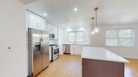 Located at 100 E Melrose Ave in Baltimore's 21212 neighborhood, this thoughtfully renovated single-floor residence blends classic architectural character with modern finishes throughout. Warm parquet hardwood floors extend across the main living areas, complementing the clean white walls and recessed lighting that give the home a bright, airy feel.

The expansive living room serves as a central gathering space, anchored by a classic fireplace with a dark tile surround and a built-in shelving unit with cabinetry on either side — a standout architectural feature that adds both charm and functionality. Natural light filters in generously through multiple windows.

The fully updated kitchen is a highlight, featuring white shaker cabinetry with gold hardware, a large central island with a contrasting dark base and quartz countertop, and a full suite of stainless steel appliances including a gas range, built-in microwave, dishwasher, and French door refrigerator. Elegant brass pendant lights hang above the island, and subway tile backsplash lines the walls. The bedrooms continue the parquet flooring aesthetic, with one room offering a built-in closet and natural views through large windows. Bathrooms are finished with marble-style tile flooring and clean white vanities with matte black hardware. An in-unit laundry area with a front-loading Whirlpool washer completes this well-appointed home.