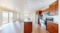 Located at 3484 Lake Butte des Morts Dr in Oshkosh, WI, this single-floor, 3-bedroom, 2-bathroom home offers a thoughtfully designed open-concept layout. The kitchen is a standout feature, showcasing rich cherry wood cabinetry, stainless steel appliances, a tile backsplash, and a central island with a granite countertop and pendant lighting overhead. The kitchen flows seamlessly into the combined dining and living area, where light wood-style flooring and multiple windows bathe the space in natural light. A welcoming entryway hallway leads directly into this open living area, providing a smooth transition throughout the home. The bedrooms are carpeted for comfort, with generous windows offering outdoor views of the surrounding landscape. Ceiling fans add functionality to the bedroom spaces. Two walk-in closets with wire shelving provide ample storage. The bathrooms feature tile flooring, warm wood vanities with granite countertops, and a tub-shower combination. The neutral color palette of soft whites and beiges throughout creates a clean, bright, and cohesive ambiance, making this home a versatile and move-in-ready space in the Oshkosh area.