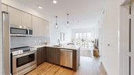 Located at 1855 Westwood Blvd in Los Angeles, this contemporary single-floor residence offers a thoughtfully designed open-concept layout with clean modern finishes throughout. The kitchen is a standout feature, equipped with stainless steel appliances including a range, built-in microwave, dishwasher, and refrigerator. Two-toned cabinetry — warm wood lower cabinets paired with light upper cabinets — frames a sleek quartz countertop and tile backsplash. A peninsula with bar seating connects the kitchen seamlessly to the living area. The bright living and dining space is anchored by large floor-to-ceiling glass doors that open to a private balcony, flooding the interior with natural light and offering open city views. Wide-plank wood-style flooring extends throughout the main living areas, complementing the crisp white walls. The bedroom features direct balcony access, generous closet space, and a serene, light-filled atmosphere. The bathroom is finished with large-format floor tiles, a soaking tub with subway tile surround, matte black fixtures, and a modern floating vanity. Recessed lighting and contemporary pendant fixtures add warmth and style. This residence combines functional design with a bright, airy ambiance in a prime Westside Los Angeles location.