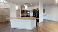 Located at 910 Ninth Ave N in Nashville, Tennessee, this single-floor residence is designed with a cohesive, contemporary aesthetic throughout. The kitchen serves as a central highlight, showcasing rich dark wood cabinetry, a tile backsplash, track lighting, and a generously sized granite-topped island with an integrated sink and pendant lighting overhead. Black appliances and a dedicated built-in desk area add both function and character to the space. Wood-style flooring extends through the main living and kitchen areas, complementing the warm, neutral color palette.

The living area features French doors with transom windows above, inviting abundant natural light and providing views of the surrounding neighborhood. A ceiling fan overhead adds to the room's comfort. The carpeted bedrooms are well-proportioned, each benefiting from natural light through standard windows and ceiling fans for year-round comfort.

Two bathrooms reflect consistent design choices, featuring dark wood vanities with white countertops, wood-style flooring, and brushed nickel hardware. One bathroom includes a soaking tub with tiled surround, while the other offers a walk-in shower. The overall ambiance throughout is clean, bright, and move-in ready.